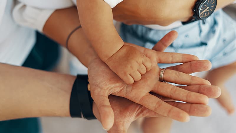 mom and dad hold baby hand